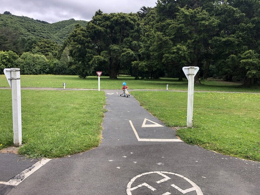 Toddler on balance bike, playing on miniature road with street signs and painted lines