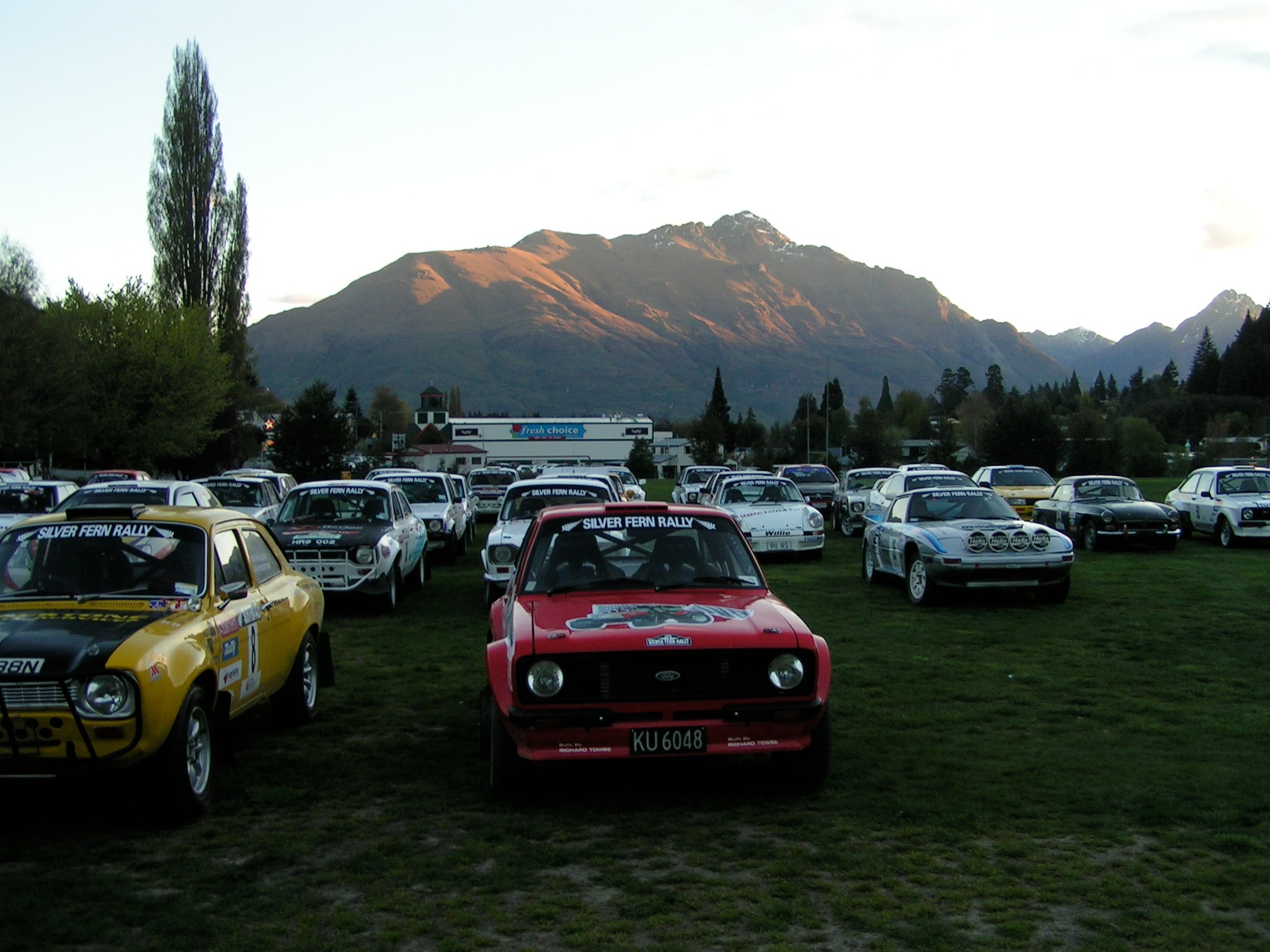 Classic rally cars lined up under the hills